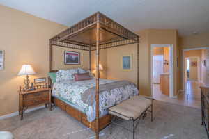 Bedroom featuring light carpet, light tile patterned floors, a textured ceiling, and baseboards