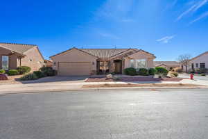 View of front of home with stucco siding, a garage, stone siding, driveway, and a tiled roof