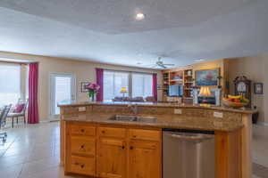 Kitchen with open floor plan, dishwasher, a sink, and light tile patterned floors