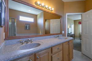 Primary Bathroom featuring tile patterned flooring, a shower with door, a sink, and double vanity