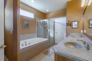 Full bath with a stall shower, tile patterned flooring, a jetted tub, upgraded corian, and dual sinks