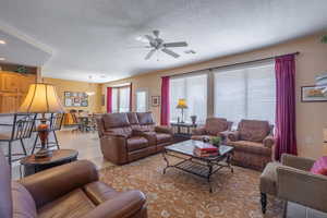 Living area with a ceiling fan, visible vents, light tile patterned flooring, and a textured ceiling