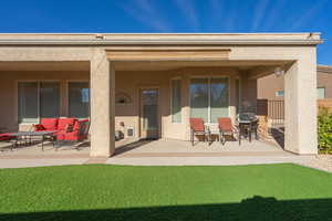 Rear view of house featuring stucco siding, fence, outdoor lounge area, and a patio