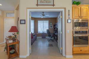 Interior space featuring light tile patterned floors, ceiling fan, a textured ceiling, and baseboards