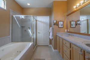 Bathroom with tile patterned flooring, a sink, a shower stall, a whirlpool tub, and double vanity