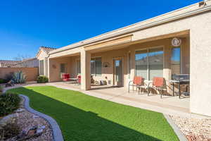 Rear view of property featuring a lawn, a patio area, fence, and stucco siding