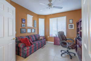 Home office with frenc doors, light tile patterned floors, ceiling fan, and baseboards