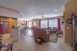 Great room with light tile patterned floors, ceiling fan, and a textured ceiling