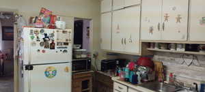 Kitchen with freestanding refrigerator, stainless steel microwave, a sink, and white cabinetry