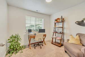 Office with baseboards, visible vents, and light colored carpet