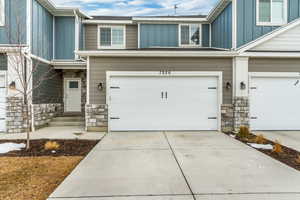 Exterior space with board and batten siding, stone siding, concrete driveway, and a garage