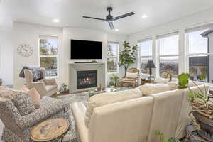 Living room with ceiling fan, a glass covered fireplace, and recessed lighting