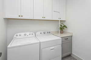 Laundry room with baseboards, cabinet space, and washer and dryer