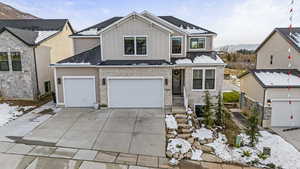 View of front of house featuring concrete driveway, roof with shingles, a mountain view, board and batten siding, and brick siding