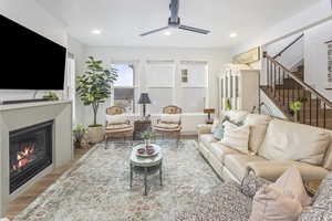 Living room with recessed lighting, light wood-style flooring, stairs, and a glass covered fireplace