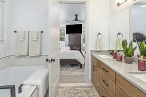 Ensuite bathroom with double vanity, a bathing tub, a sink, ensuite bath, and tile patterned flooring