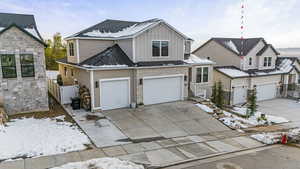 View of front facade featuring board and batten siding, driveway, an attached garage, and fence