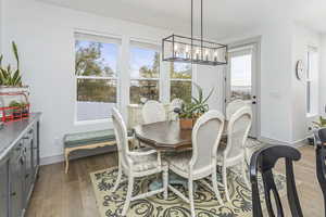 Dining space with a notable chandelier, light wood-type flooring, and baseboards