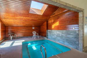 View of swimming pool featuring an indoor hot tub, a swimming pool, and a skylight