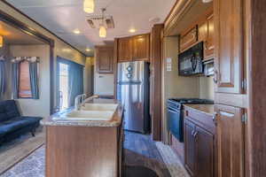 Kitchen featuring decorative light fixtures, stainless steel appliances, visible vents, a sink, and an island with sink