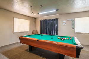 Playroom with a textured ceiling, carpet floors, and visible vents