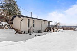 View of rear of property with central AC, brick siding, and stairway.