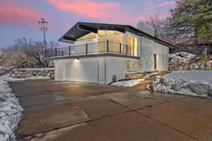 View of home's exterior featuring a garage, concrete driveway, and a covered deck.