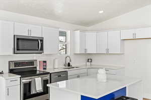 Kitchen featuring a center island, stainless steel appliances, quartz countertops, and white cabinetry.