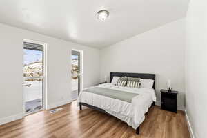 Primary bedroom with floor to ceiling windows, and light wood finished floors.