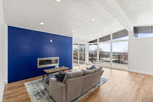 Living area with a large fireplace, floor to ceiling windows, and vaulted ceiling with beams.