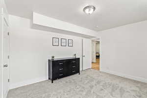 Bedroom with light colored carpet, a textured ceiling, and windows.