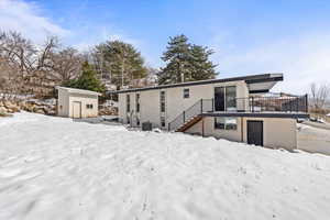 View of rear of property with central AC, shed, brick siding, and stairway to covered deck.