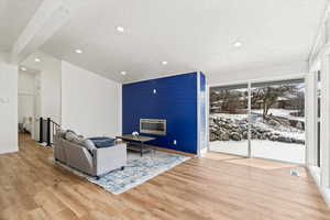 Living area with a large fireplace, floor to ceiling windows, and vaulted ceiling with beams.