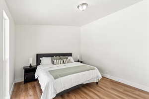 Primary bedroom with floor to ceiling windows, and light wood finished floors.