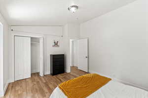 Bedroom featuring light wood LVP flooring, a closet, and vaulted ceiling.