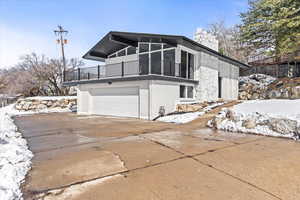 Exterior of property featuring concrete driveway, a chimney, and an attached garage