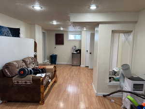 Living area featuring a textured ceiling, baseboards, heating unit, and light wood-style floors