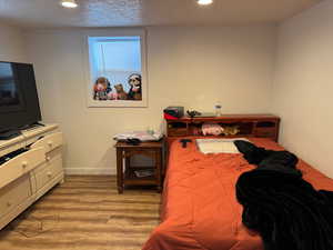 Bedroom with a textured ceiling, baseboards, wood finished floors, and recessed lighting