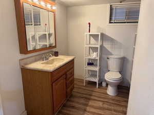 Half bathroom featuring vanity, toilet, and wood finished floors