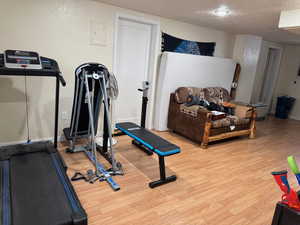 Exercise area with a textured ceiling, baseboards, and wood finished floors