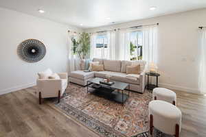 Living room with recessed lighting, visible vents, baseboards, and wood finished floors