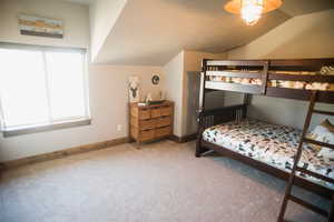 Carpeted bedroom featuring lofted ceiling, baseboards, and a textured ceiling