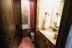 Full bathroom featuring toilet, tile patterned floors, shower / bath combo with shower curtain, and vanity