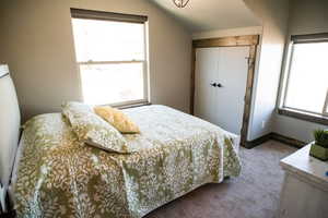 Carpeted bedroom featuring lofted ceiling, baseboards, and a closet