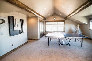Recreation room with lofted ceiling with beams, a textured ceiling, carpet, and baseboards