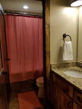 Full bath featuring a shower with shower curtain, vanity, and toilet