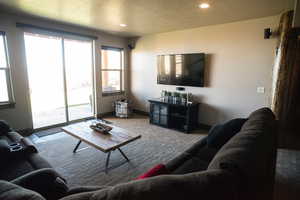 Carpeted living room featuring recessed lighting, a textured ceiling, and baseboards