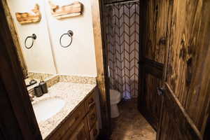 Bathroom featuring toilet, curtained shower, and vanity