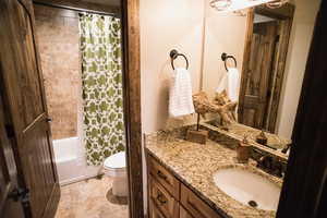 Bathroom with shower / bath combination with curtain, vanity, and toilet