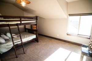 Bedroom featuring lofted ceiling, carpet flooring, and baseboards